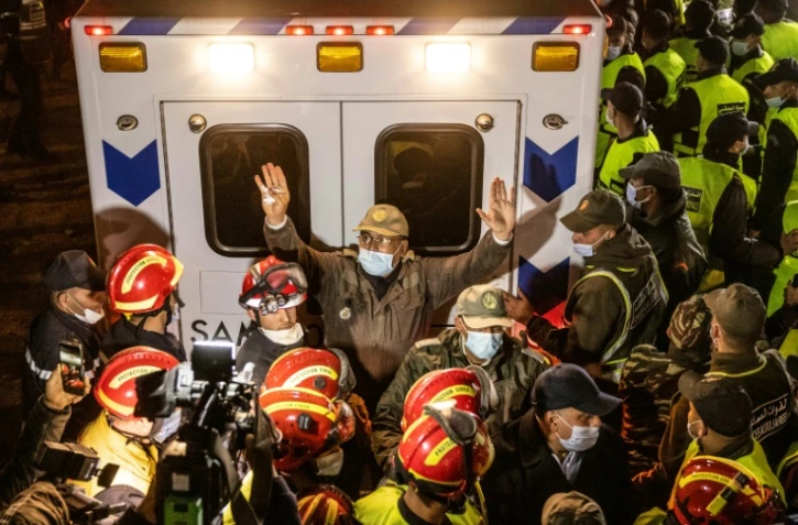 Des membres des forces de sécurité marocaines et des secouristes devant l'ambulance transportant le corps du petit Rayan après son extraction d'un puits à Ighrane, le 5 février 2022