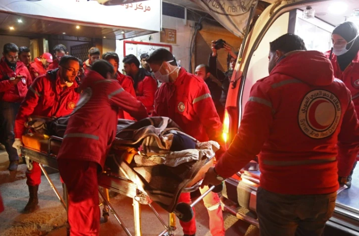 Des volontaires du Croissant rouge syrien évacuent un civil malade de Douma, ville rebelle assiégée près de Damas, tard le 28 décembre 2017