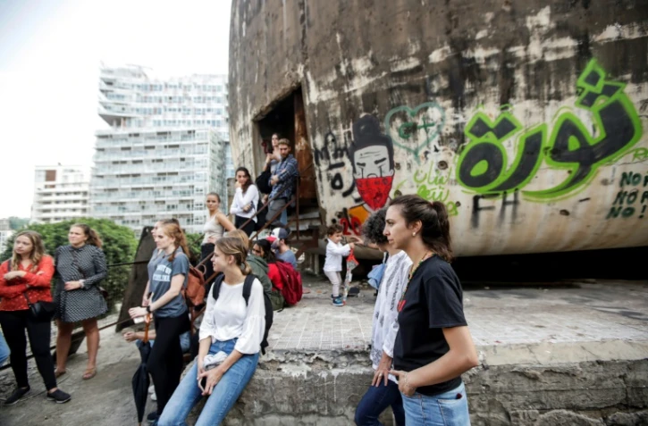 Des étudiants assistent, tournant le dos à "L'oeuf", une structure emblématique en béton au toit oblong à moitié en ruines, à un cours sur la politique des espaces publics à Beyrouth le 24 octobre 2019