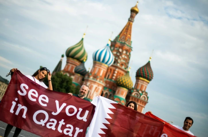 Des personnes déploient une banderole "à bientôt Qatar" sur la Place Rouge de Moscou, à la veille de la finale du Mondial-2018 en Russie, le 14 juillet 2018