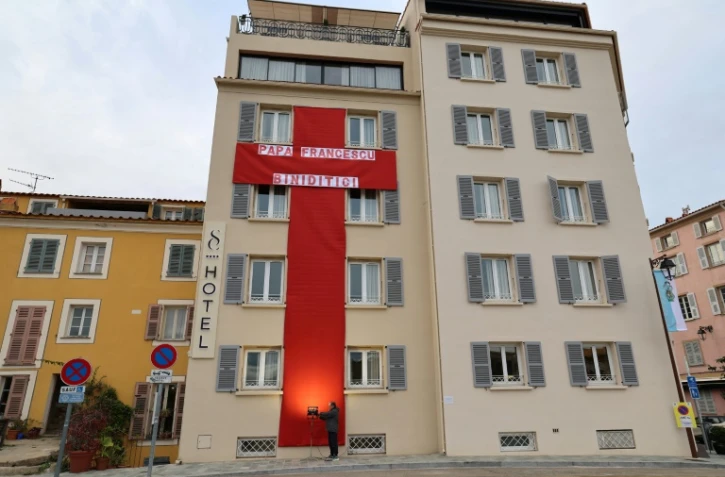 Une immense croix rouge en tissu accrochée à la façade d'un hôtel pour la visite du pape François à Ajaccio, le 12 décembre 2024 en Corse