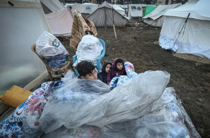 De jeunes Palestiniens sont assis sur des matelas recouverts de plastique dans un camp pour personnes déplacées à Rafah, dans le sud de la bande de Gaza, le 13 décembre 2023