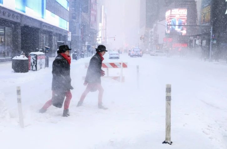 Des passants sur la 6e avenue en pleine tempête de neige à New York le 25 janvier 2026