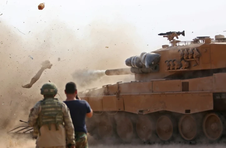 Des soldats turcs observent un char de leur armée tirer sur des positions d'une milice kurde, à Ras al-Aïn (nord de la Syrie), le 28 octobre 2019