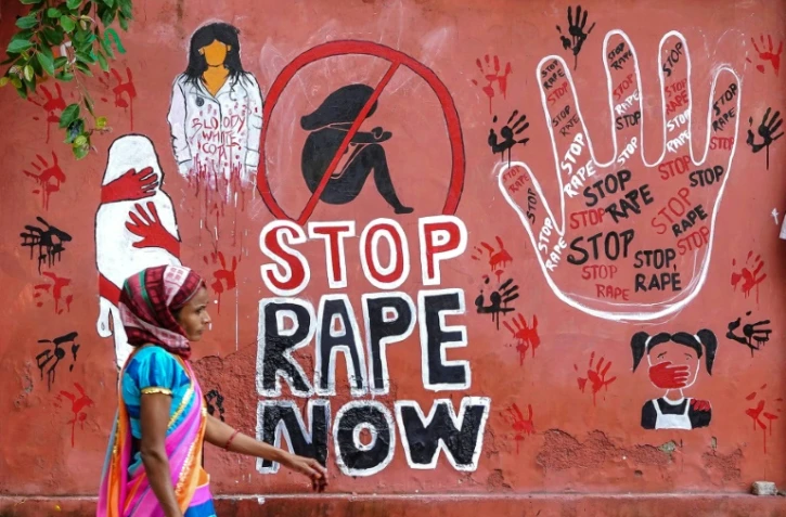 une femme passe devant une fresque murale dénonçant les viols en Inde, le 17 août 2024 à Ajmer