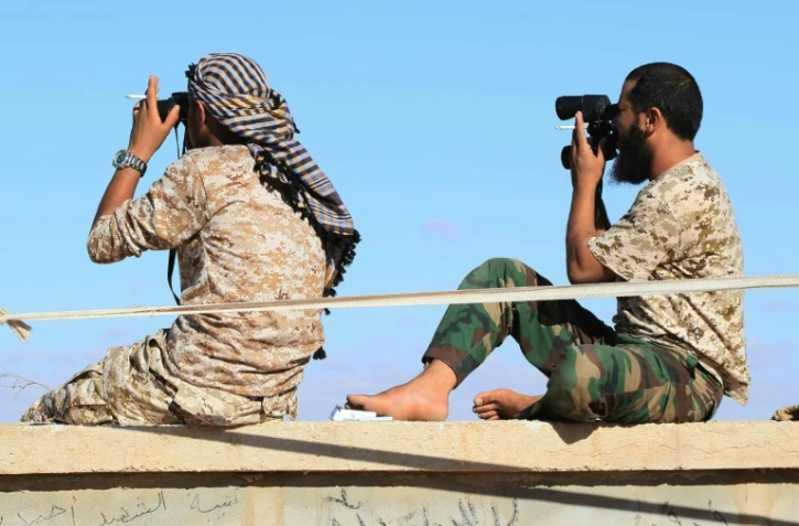 Des soldats libyens loyaux au gouvernement libyen d'union nationale (GNA) observent Syrthe alors qu'ils s'apprĂŞtent Ă attaquer cette ville tenue par l'EI, le 18 juillet 2016