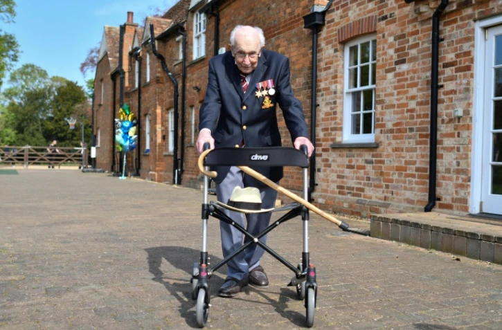 Le capitaine Tom Moore, un ancien combattant âgé de 99 ans, marche le long de son jardin avec son déambulateur pour lever des fonds destinés au NHS, dans le village de Marston Moretaine au nord de Londres le 16 avril 2020
