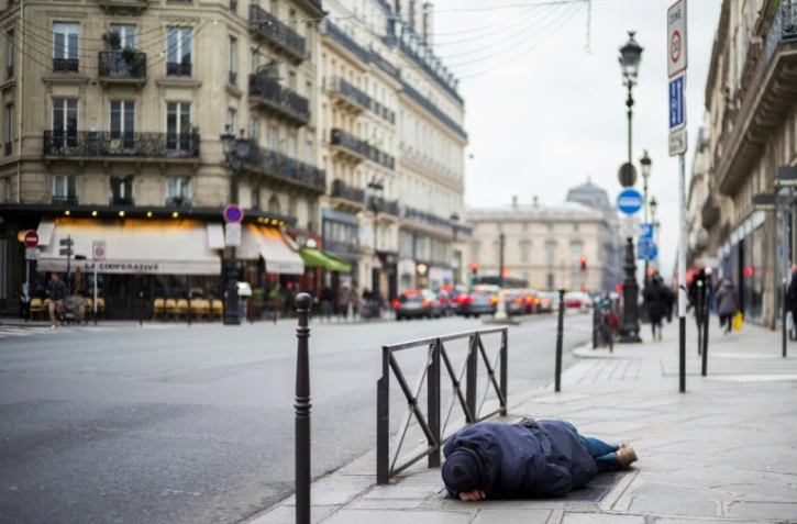 Un SDF dort le 16 janvier 2017 sur le trottoir à Paris où une vague de froid est attendue dans les prochains jours