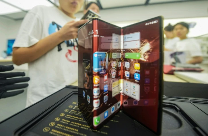 Le nouveau téléphone pliable à trois volets du géant chinois de la technologie Huawei, le Huawei Mate XT, est présenté lors de son jour de lancement dans un magasin Huawei à Hangzhou, dans la province du Zhejiang, dans l'est de la Chine, le 10 septembre 2024