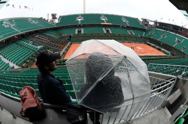 Une personne s'abrite sous un parapluie en attendant le début des matches (finalement annulés) en raison d'une pluie persistante  sur Roland-Garros, le 30 mai 2016