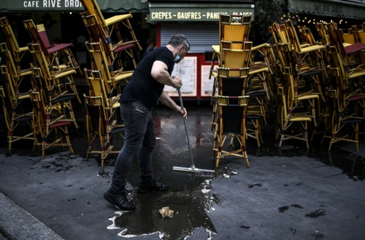 Un employé nettoie la terrasse d'un café à Paris le 12 mai en vue de la réouverture des terrasses le 19 mai 2021
