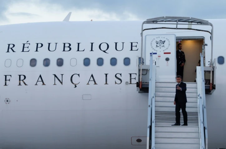 Le président français Emmanuel Macron fait un signe de la main en embarquant dans son avion présidentiel pour se rendre en Nouvelle-Calédonie, à l'aéroport d'Orly, en banlieue de Paris, le 21 mai 2024