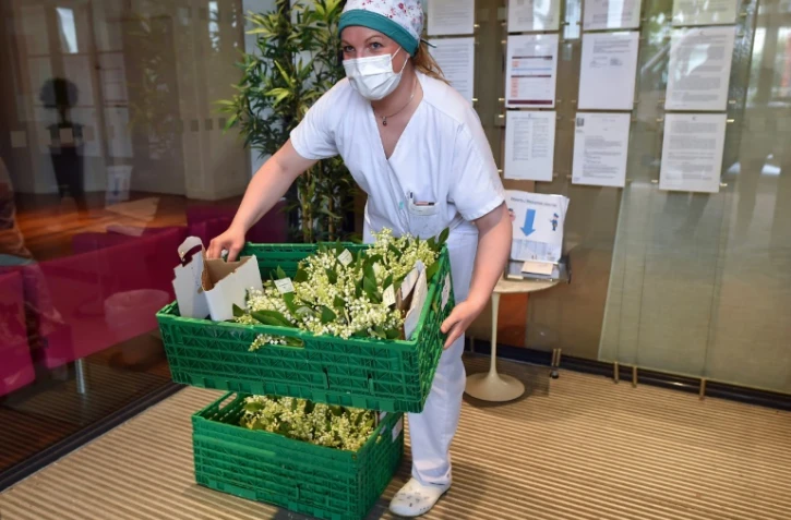 Un membre de l'équipe des soignants travaillant dans un Ehpad à Saint-Martin-du-Touch, près de Toulouse, réceptionne des bouquets de muguets distribués par le Secours populaire, le 30 avril 2020