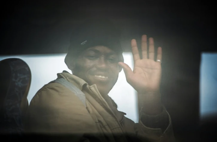 Un homme salue par la fenêtre d'un bus qui transporte des migrants, principalement soudanais, de Calais à des centre de "répit", le 27 octobre 2015