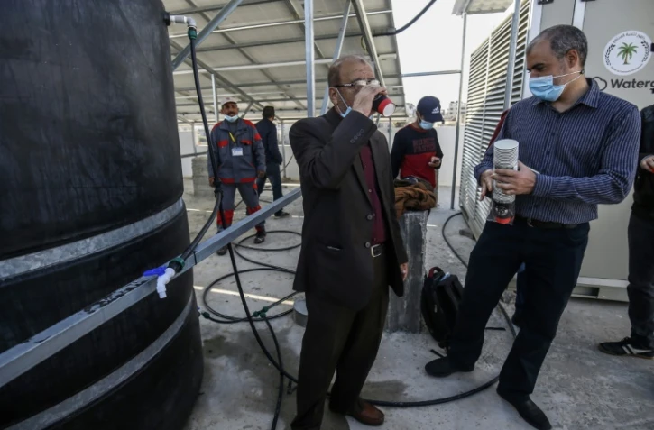 Un ingénieur boit de l'eau produite par un appareil retirant l'humidité de l'air, à Khan Younès (Gaza) le 16 novembre 2020