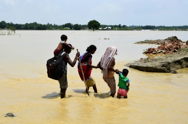 Des Népalais cheminent dans des eaux inondées le 15 août 2017 dans la région de Saptari, au sud-est de Katmandou