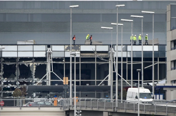 Des ouvriers marchent sur le toit de l'aéroport de Bruxelles à Zaventem le 23 mars 2016 au lendemain des attentats terroristes dans la capitale belge