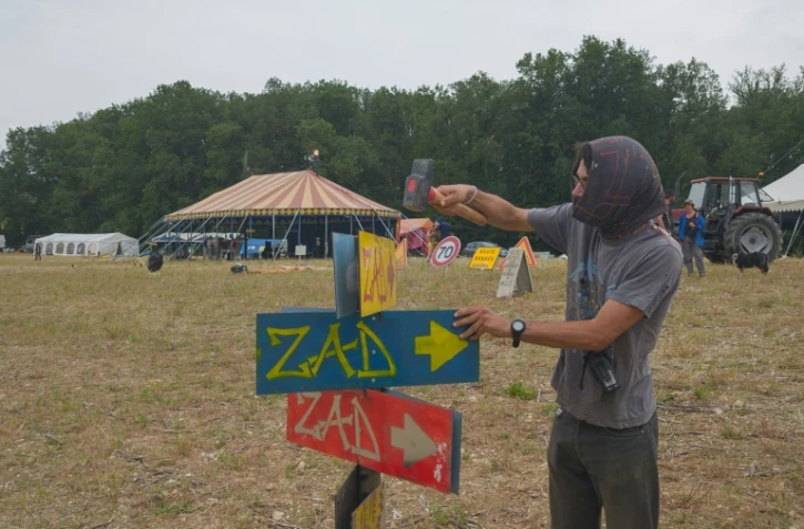 Un manifestant installe des pancartes "ZAD" (Zone à défendre) alors que des militants arrivent à un campement mis en place pour protester contre le projet d'autoroute A69 entre Toulouse et Castres, près de Puylaurens, le 7 juin 2024 dans le Tarn