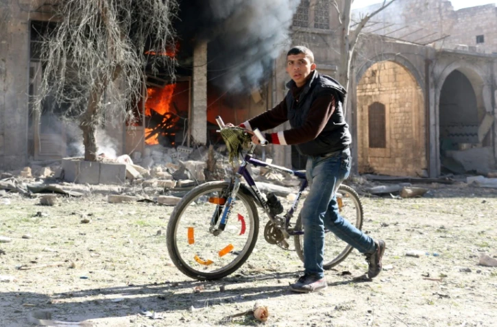 Un habitant d'un quartier assiégé d'Alep-Est passe devant une maison en feu, le 19 novembre
