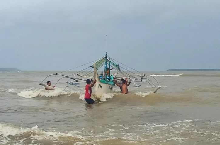 Des Philippins mettent en sécurité un bateau de pêche sur la côte à Borongan, dans le centre des Philippines, le 2 décembre 2019 à l'approche du typhon Kammuri
