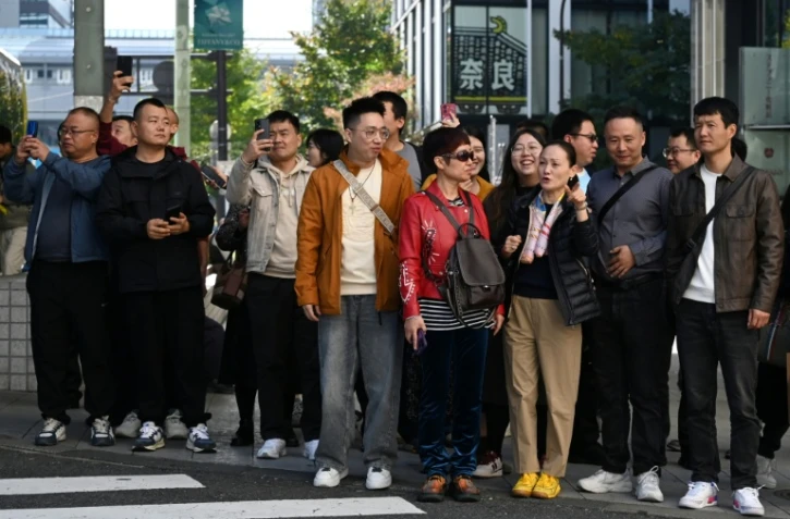 Un groupe de touristes chinois attend pour traverser une rue dans le quartier commerçant de Ginza, à Tokyo, le 16 novembre 2025