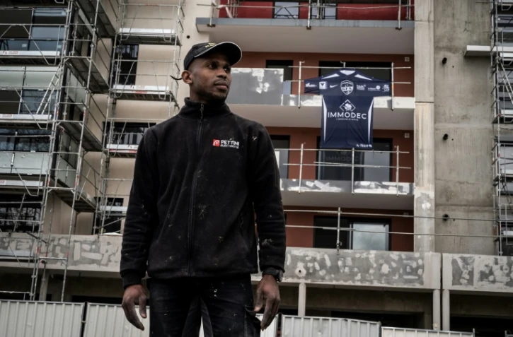 Le dĂ©fenseur de Rumilly-Vallières, Houssame Boinali, pose devant la rĂ©sidence en construction Ă Rumilly oĂą il travaille, avant d'aller Ă l'entraĂ®nement, le 11 mai 2021 au stade d’Annecy, oĂą aura lieu, dans deux jours, la demi-finale de la Coupe de France contre Monaco