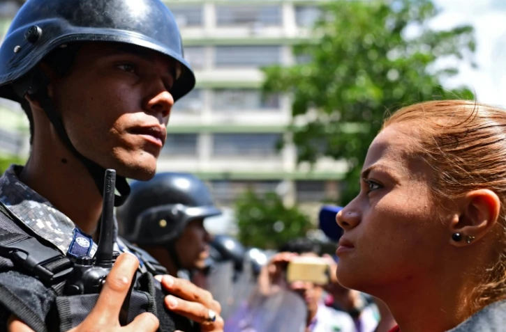 Une partisane du président autoproclamé vénézuelien Juan Guaido fait face à un policier lors d'une manifestation à Caracas le 9 mars 2019