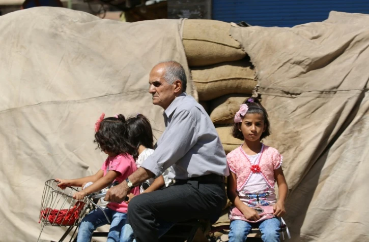 Un homme circule Ă bicyclette avec deux fillettes le 13 septembre 2016 Ă Qamishli au nord-est de la Syrie