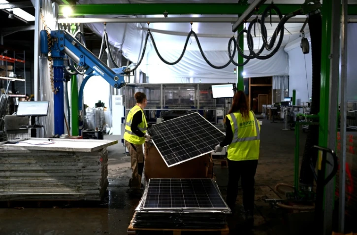 Des employées de l'entreprise Envie 2E passent dans une machine un panneau solaire usagé pour le recyclage de ses pièces, le 13 novembre 2023 à Saint-Loubès, en Gironde