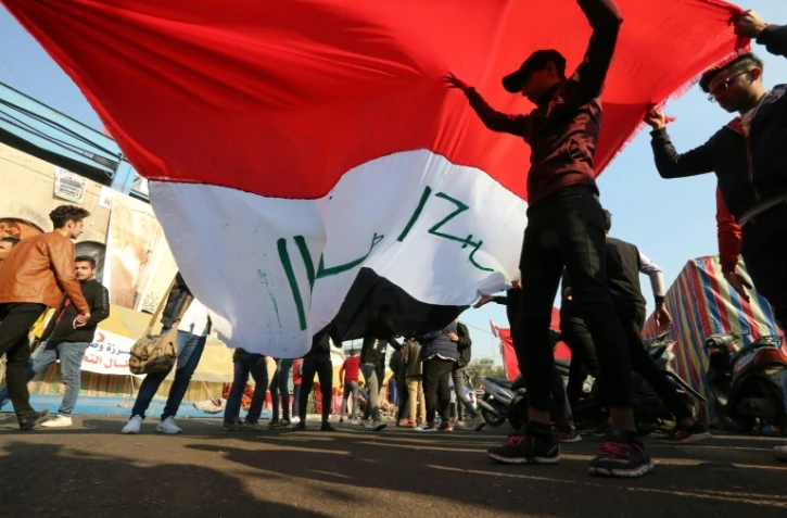 Des manifestants irakiens soulèvent un drapeau sur la place Tahrir à Bagdad, le 22 décembre 2019