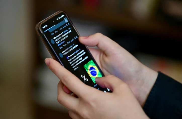Un utilisateur brésilien du réseau social X, anciennement Twitter, consulte des messages sur un téléphone portable à Brasilia, le 31 août 2024