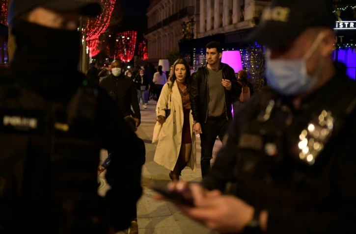 Des badauds sans masque passent à côté d'un contrôle de police sur les Champs Elysées à Paris, le 31 décembre 2021