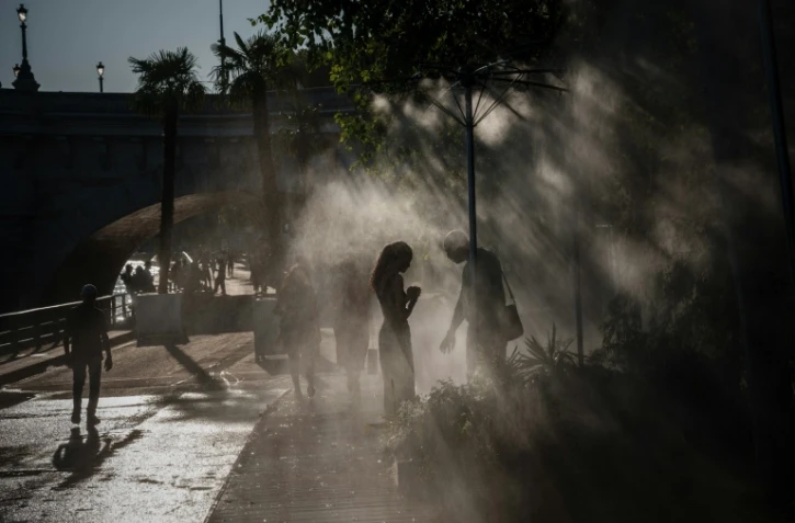 Des personnes se rafraîchissent sous des brumisateurs à Paris, le 10 juillet 2026