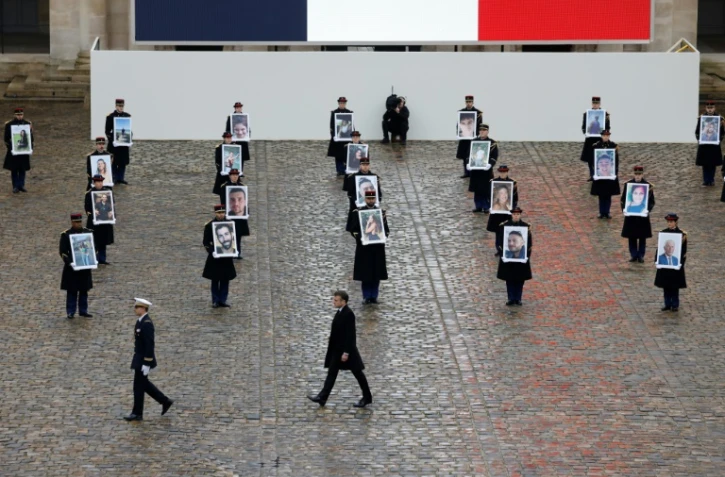 Emmanuel Macron marche devant la Garde républicaine tenant les portraits des Français et Franco-Israéliens tués, lors d'une cérémonie d'hommage aux victimes françaises de l'attaque du Hamas contre Israël le 7 octobre, aux Invalides à Paris, le 7 février 2024