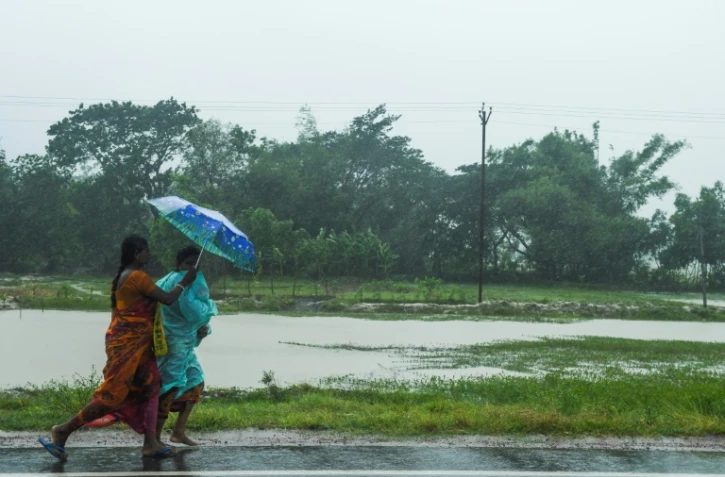 Deux femmes marchent sur la route avant l'arrivée du cyclone Amphan, à Midnapore, en Inde, sur le golfe du Bengale, le 20 mai 2020
