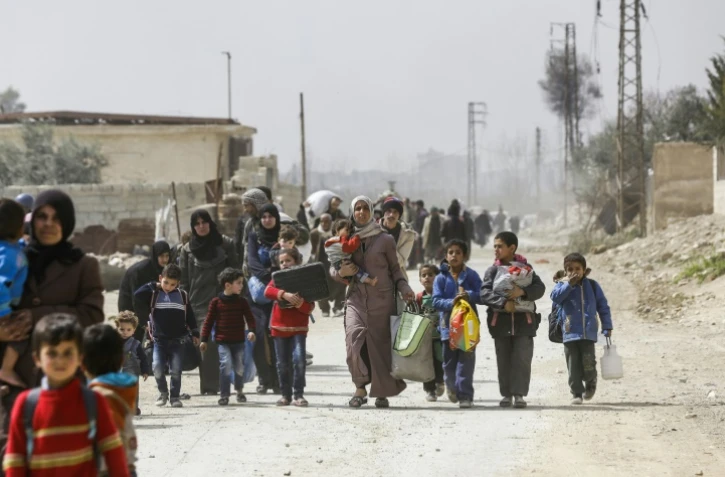 Des civils syriens évacués de la Ghouta orientale à travers un couloir contrôlé par le régime à Hoch al-Achaari, près de la capitale Damas, le 15 mars 2018