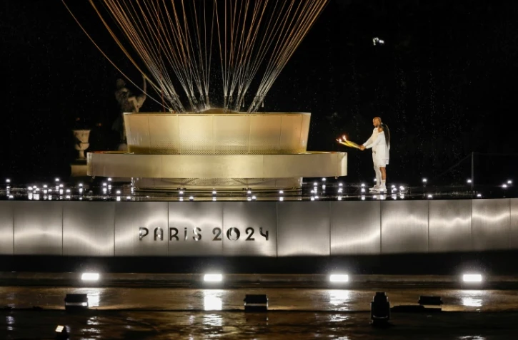 Les porteurs de la flamme olympique Marie-José Pérec et Teddy Rinner enflamment la vasque olympique lors de la cérémonie d'ouverture des JO-2024 à Paris le 26 juillet 2024.