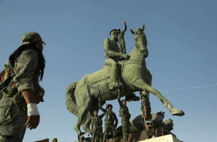 Des combattants kurdes de l'YPG et la police posent sous une statue de Basel al-Assad, frère du président syrien, à Hassaké le 23 août 2016
