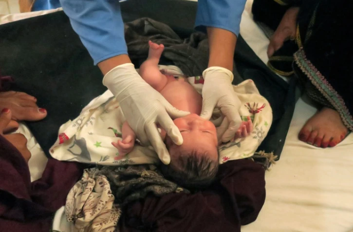 Une sage-femme afghane de Médecins sans Frontières (MSF) vérifie l'état de santé d'un nouveau-né dans une maternité, le 8 août 2018 à Khots, en Afghanistan