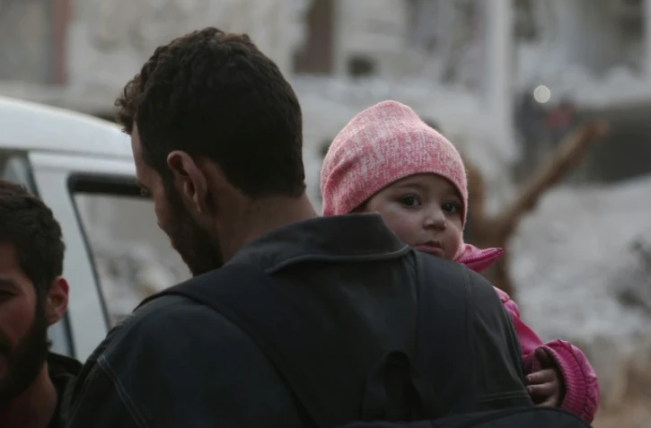 Un enfant syrien et son père se préparant à évacuer une des dernières zones rebelles dans la Ghouta orientale, près de Damas. Photo prise à Arbine,le 24 mars 2018