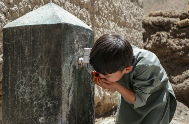 Un enfant boit de l'eau au robinet d'une fontaine à Qavariyak, dans la province de Bamiyan, le 18 juin 2025 en Afghanistan