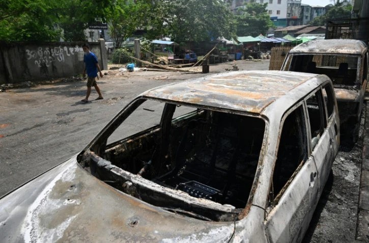 Des véhicules incendiés dans une rue de Rangoun en Birmanie le 15 mars 2021 au lendemain de manifestations contre le coup d'Etat militaire durement réprimées