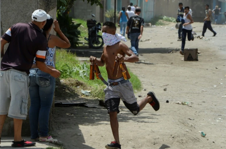 Un pillard s'enfuit avec des bouteilles de bière volées dans un magasin mis à sac à Maracay, le 27 juin 2017.
