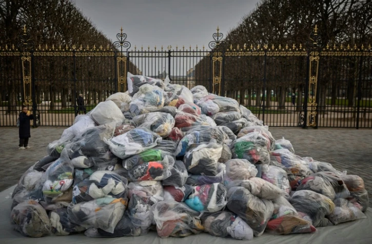 Des sacs de déchets textiles devant la porte du Palais du Luxembourg, où se trouve le Sénat lors d'une manifestation contre la fast-fashion, à Paris, le 14 mars 2025