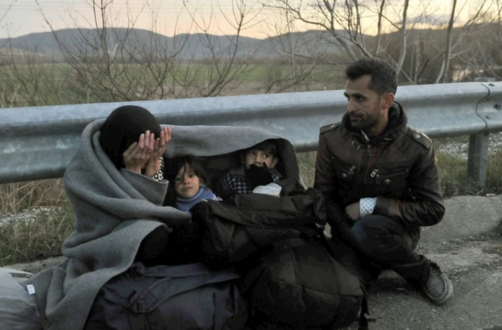 Une famille de réfugiés attend de passer la frontière entre la Grèce et la Macédoine, près du village grec d'Idomeni, dans la nuit du 21 février 2016