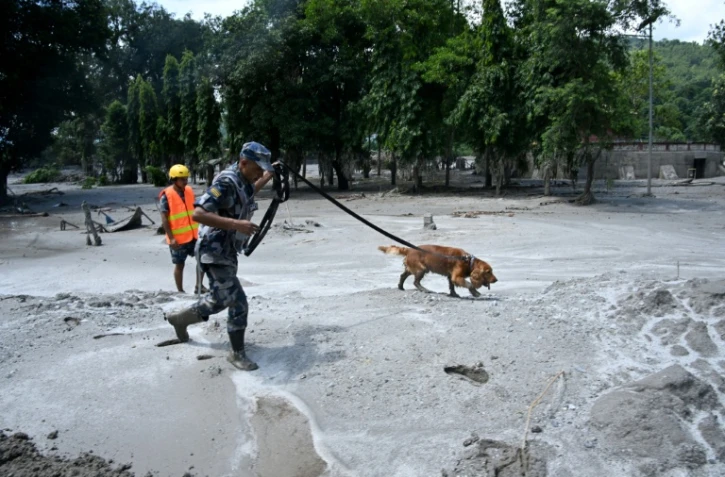 Un membre des forces de sécurité et son chien recherchent des survivants à la suite des inondations à Trishuli au Népal, le 27 août 2026