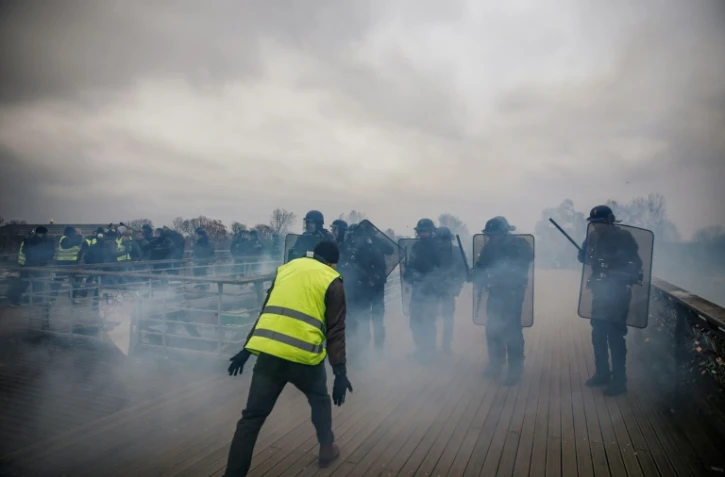Un "gilet jaune" face à des policiers anti-émeutes, sur un pont parisien le 5 janvier 2019