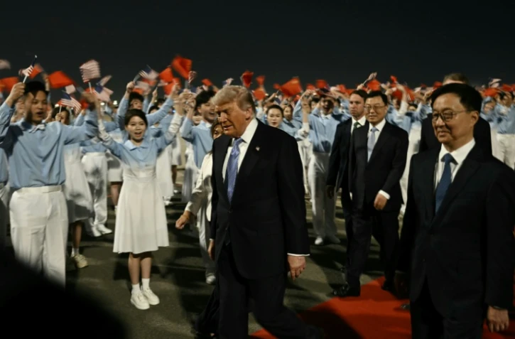 Le président américain Donald Trump (c) accompagné par le vice-président chinois Han Zheng (d) à son arrivée à l'aéroport international de Pékin, le 13 mai 2026