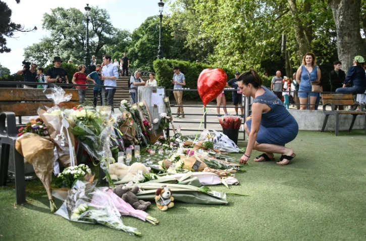 Une femme dépose des fleurs en hommage aux victimes d'une attaque au couteau à Annecy, le 9 juin 2023 aux "Jardins de l'Europe" de la ville, dans les Alpes françaises