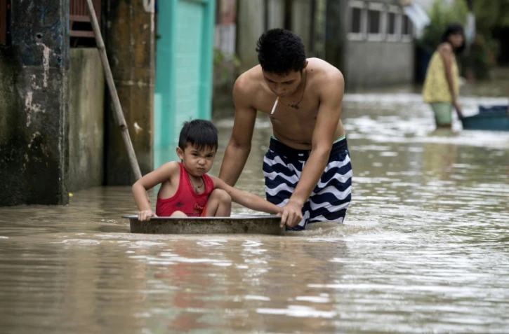 Un père pousse son fils dans une bassine dans une rue inondée par le typhon Mangkhut à Bulacan, aux Philippines, le 16 septembre 2018.